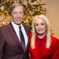a man and women take photo in front of Christmas tree
